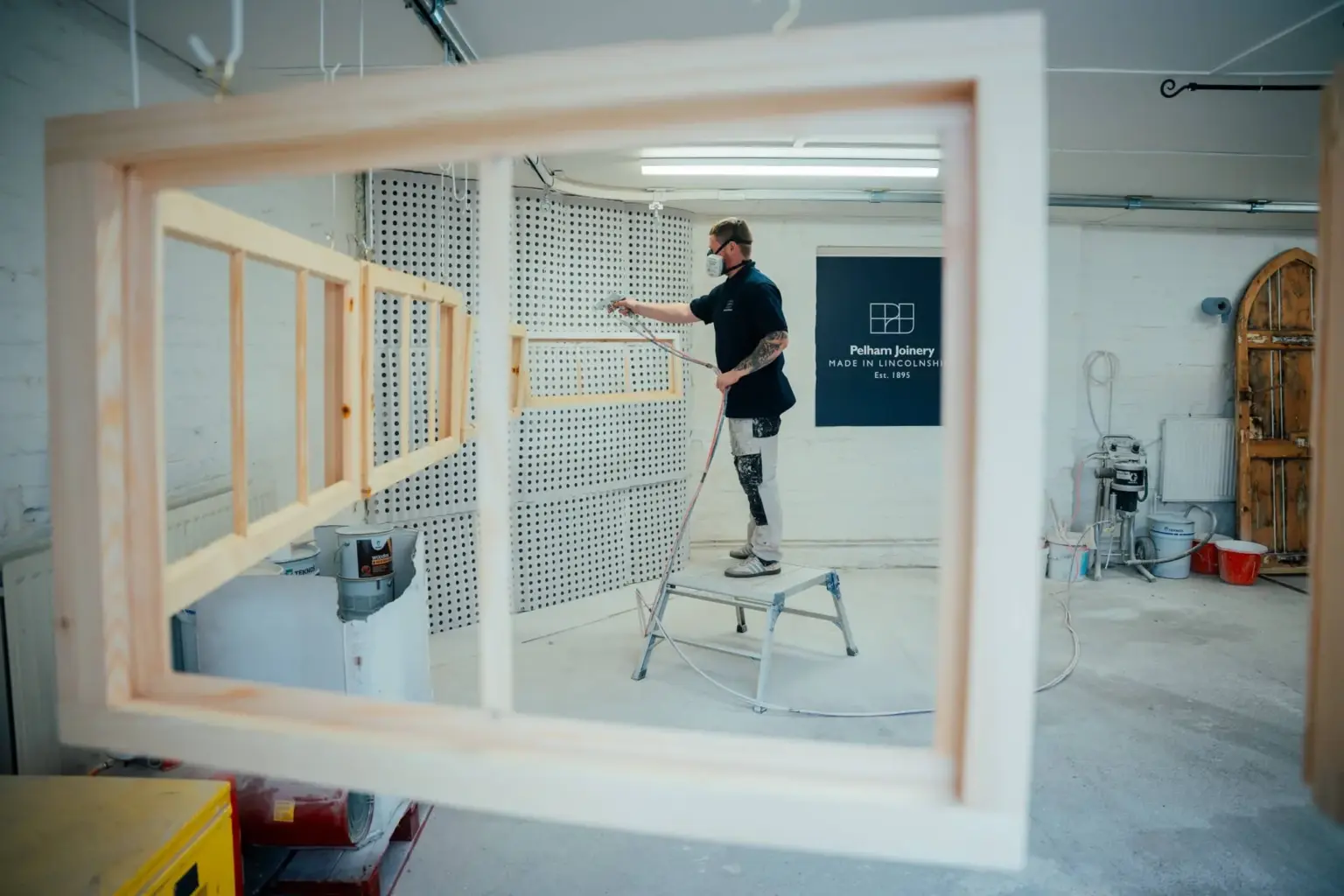 Joiner spray finishing a bespoke window at Pelham Joinery, Lincolnshire