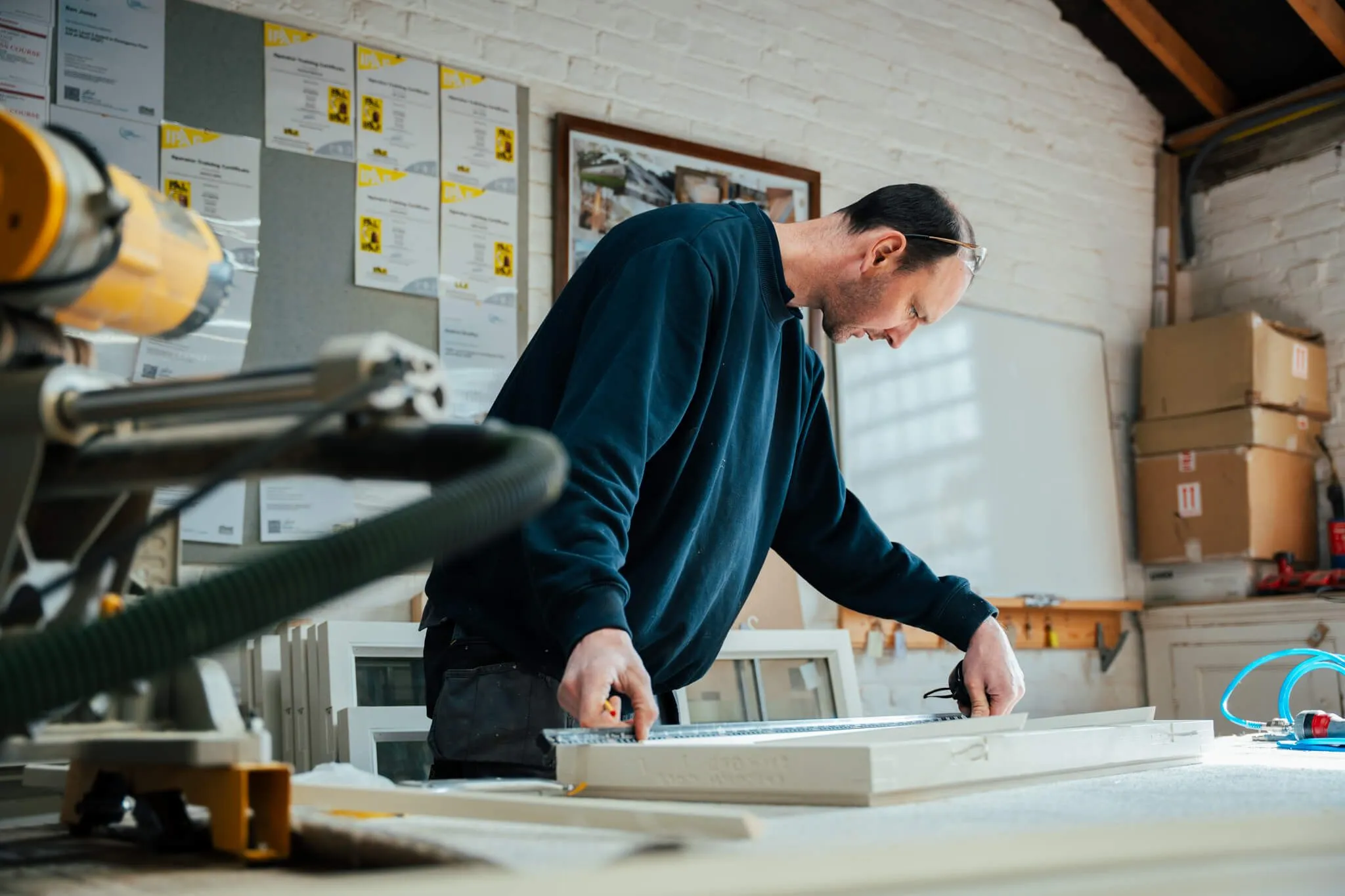 Joiner leaning over a work bench measuring a bespoke window frame